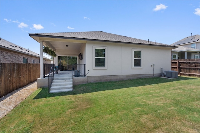 rear view of house with central air condition unit and a lawn