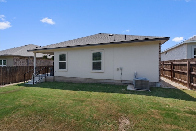 rear view of property with a yard and central AC