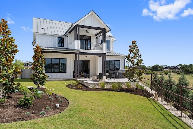 rear view of property featuring ceiling fan, a balcony, an outdoor living space, a yard, and a patio area