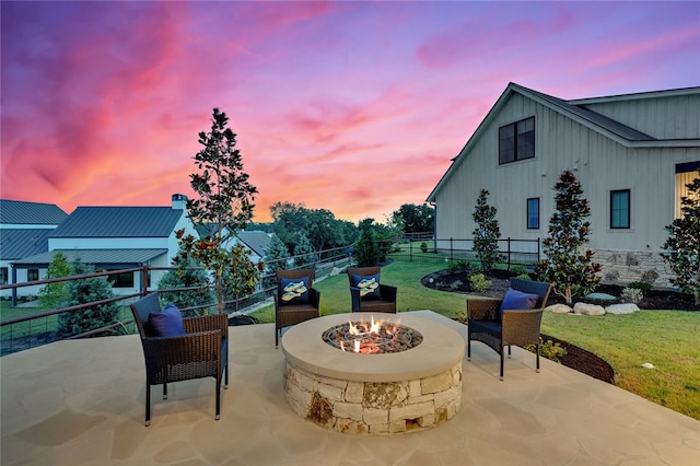 patio terrace at dusk with a fire pit and a lawn