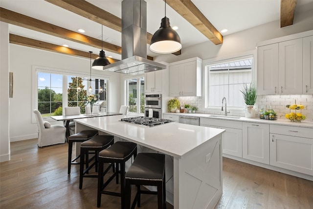 kitchen featuring beamed ceiling, hardwood / wood-style flooring, sink, and island range hood