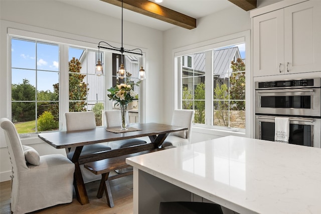 dining area with plenty of natural light, beamed ceiling, and wood-type flooring