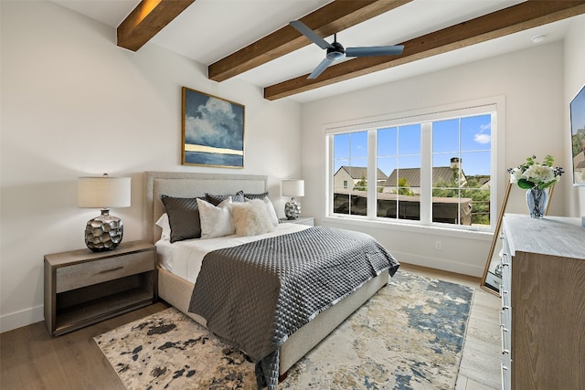 bedroom with ceiling fan, beamed ceiling, and light wood-type flooring