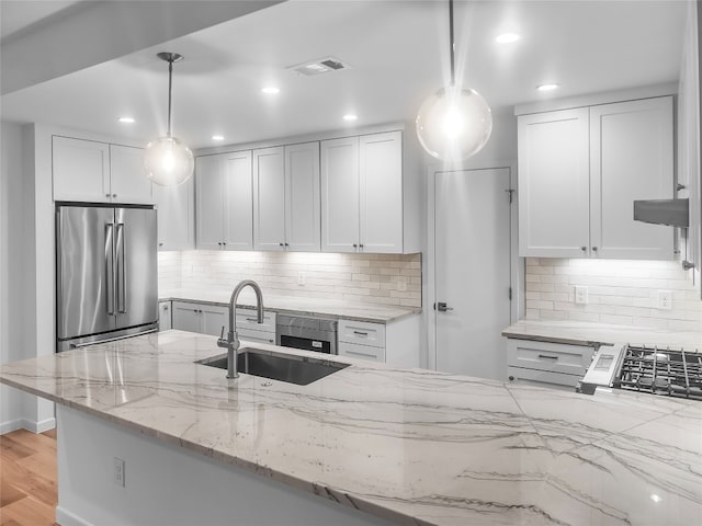 kitchen featuring decorative backsplash, hanging light fixtures, light hardwood / wood-style floors, and high end refrigerator