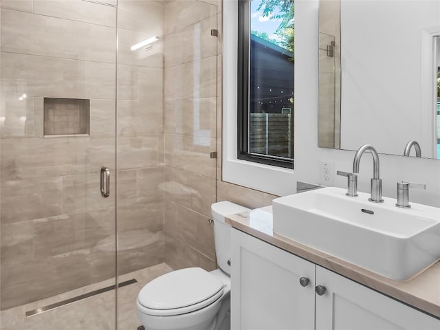 bathroom featuring toilet, tile walls, vanity, and a shower with shower door