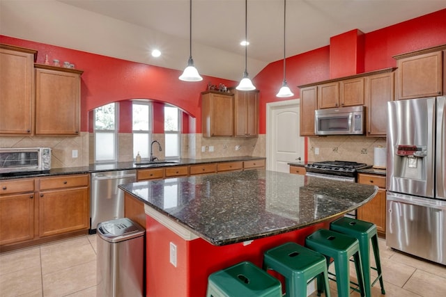 kitchen with tasteful backsplash, a breakfast bar area, sink, a kitchen island, and stainless steel appliances