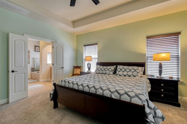 bedroom featuring light carpet, multiple windows, ensuite bathroom, and ceiling fan