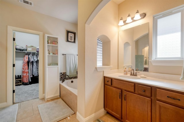 bathroom featuring tile patterned floors, tiled tub, and vanity