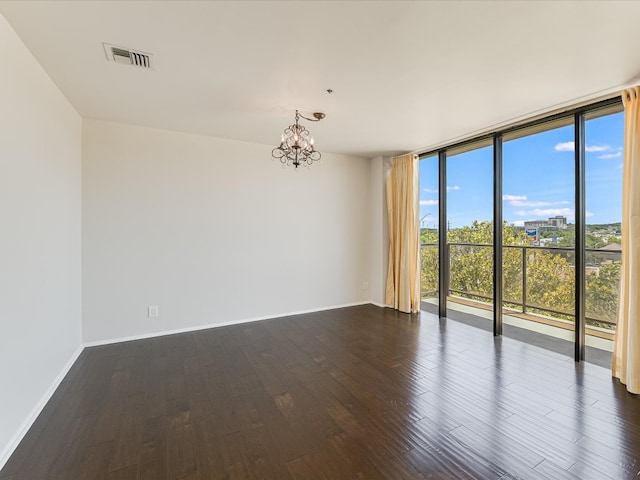 empty room featuring expansive windows, hardwood / wood-style floors, and an inviting chandelier