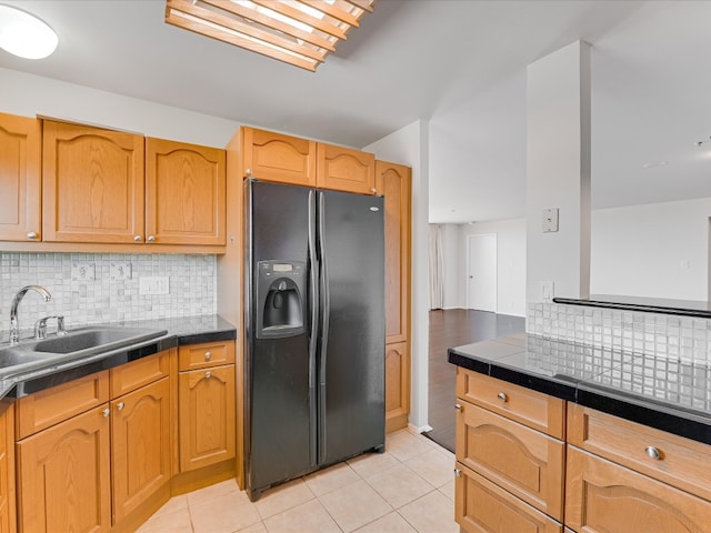 kitchen with decorative backsplash, sink, tile countertops, black fridge with ice dispenser, and light tile patterned flooring