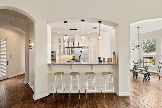 2413 Never Bend Cv, Austin, TX 78746 - kitchen with stainless steel appliances, a chandelier, ornamental molding, glass insert cabinets, and dark wood-style floors