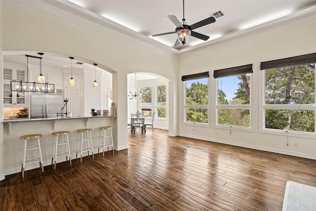 interior space featuring ornamental molding, arched walkways, dark wood-style flooring, and visible vents