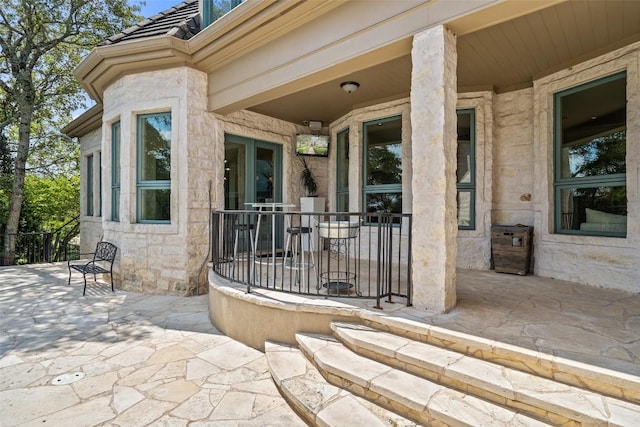 entrance to property with stone siding and a patio