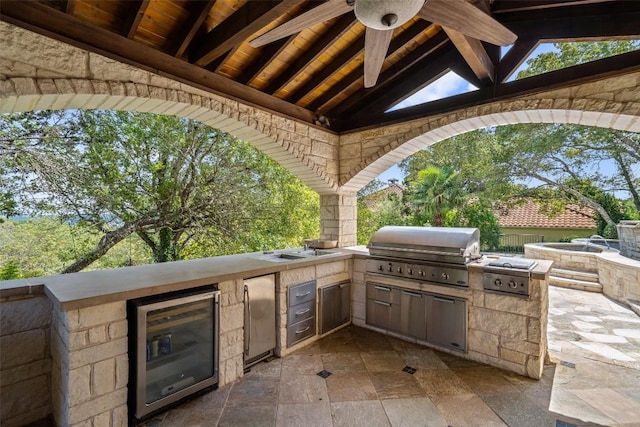 view of patio / terrace featuring beverage cooler, an outdoor kitchen, and grilling area