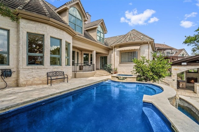 back of property featuring an outdoor pool, an outdoor stone fireplace, a patio, and an in ground hot tub