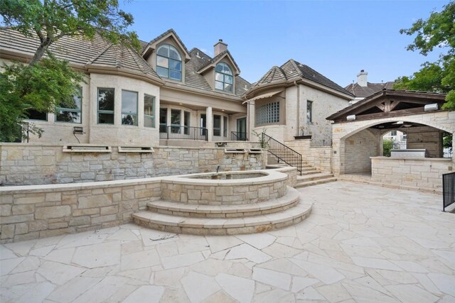 back of house with area for grilling, outdoor dry bar, stucco siding, a chimney, and a patio area