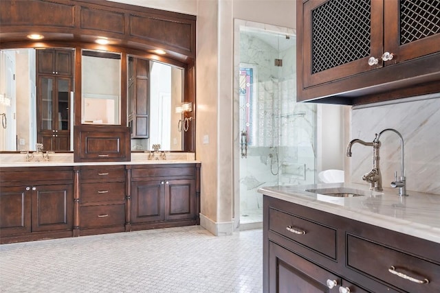 bathroom with double vanity, a marble finish shower, and a sink