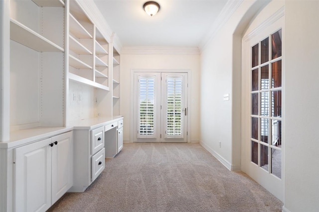 interior space with baseboards, french doors, light colored carpet, and crown molding