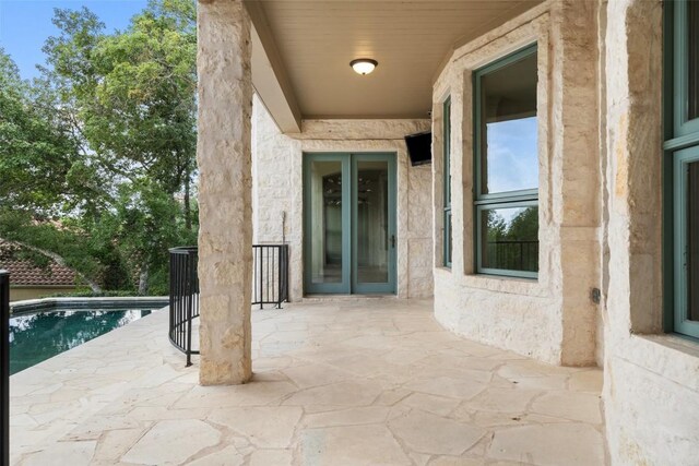 view of exterior entry with a patio area and an outdoor pool