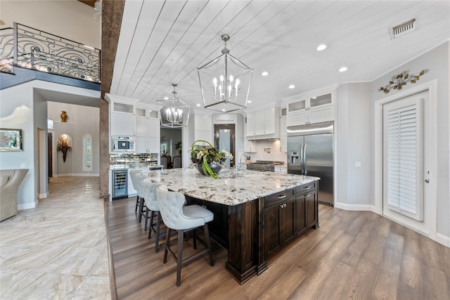 kitchen featuring white cabinetry, stainless steel built in refrigerator, wood-type flooring, and decorative backsplash