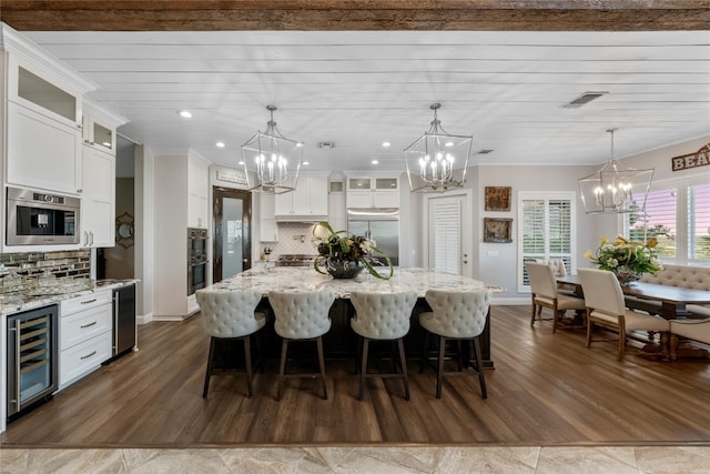 kitchen featuring appliances with stainless steel finishes, dark wood-type flooring, decorative backsplash, and beverage cooler