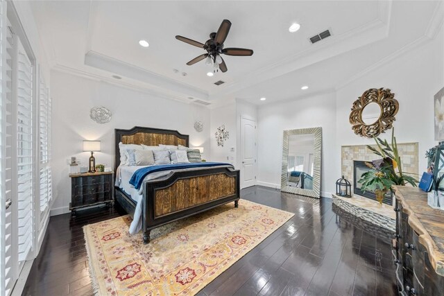 bedroom with ceiling fan, a raised ceiling, crown molding, and dark hardwood / wood-style flooring