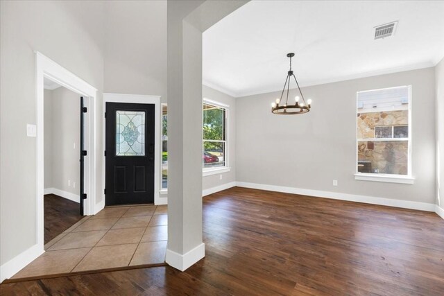 tiled entryway with crown molding and a chandelier