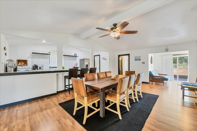 dining room with ceiling fan, light hardwood / wood-style flooring, and vaulted ceiling with beams