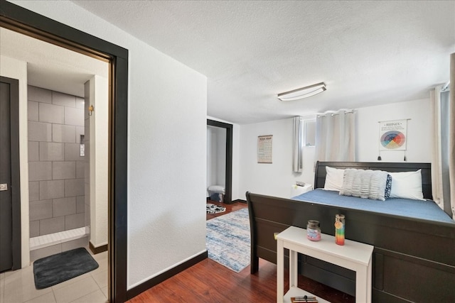 bedroom with a textured ceiling, tile walls, and hardwood / wood-style flooring