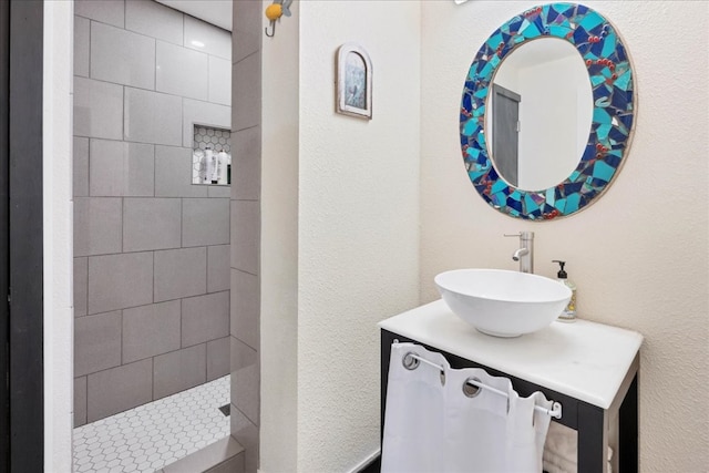 bathroom featuring a tile shower and vanity