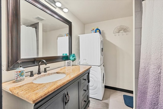 bathroom with tile patterned flooring, stacked washing maching and dryer, and vanity