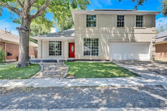 traditional-style house featuring driveway, a front yard, a garage, and brick siding