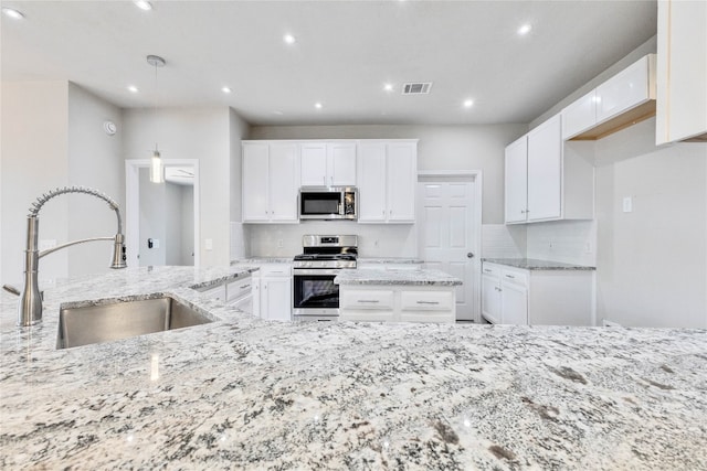 kitchen featuring white cabinetry, appliances with stainless steel finishes, light stone counters, and backsplash