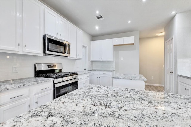 kitchen with appliances with stainless steel finishes, white cabinetry, and visible vents