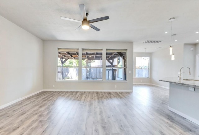 unfurnished living room featuring light wood-style floors, ceiling fan, visible vents, and a sink