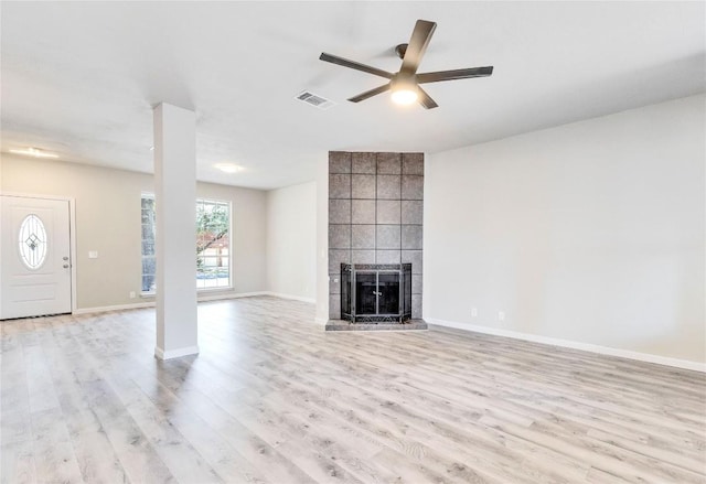 unfurnished living room with a large fireplace, light wood finished floors, visible vents, baseboards, and ceiling fan