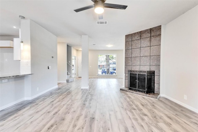 unfurnished living room with a fireplace, visible vents, stairway, light wood-style flooring, and baseboards