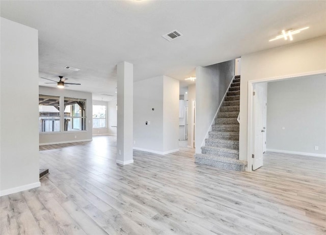 interior space featuring baseboards, visible vents, light wood finished floors, and stairs