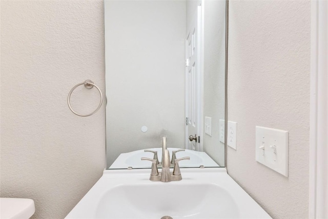 half bath with a textured wall and toilet