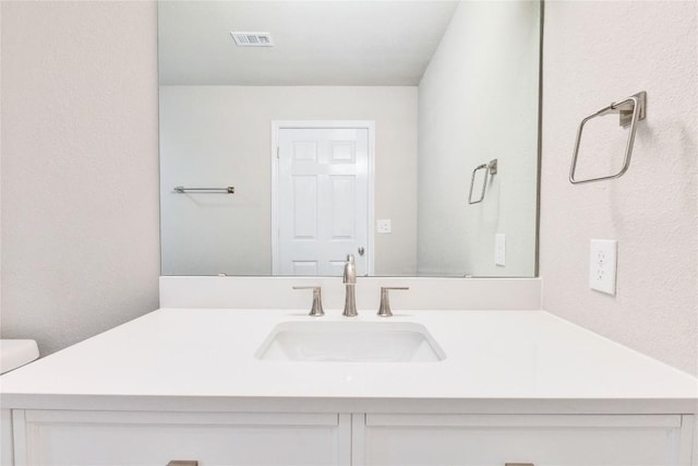 bathroom featuring toilet, visible vents, and vanity