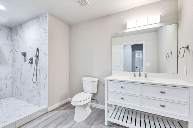 full bath with toilet, wood finished floors, vanity, visible vents, and a marble finish shower