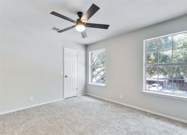 carpeted spare room featuring ceiling fan, a textured ceiling, visible vents, and baseboards