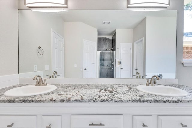 bathroom featuring double vanity, a shower stall, visible vents, and a sink