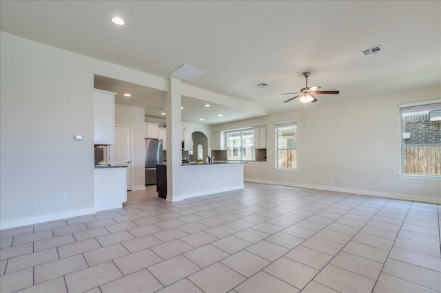 unfurnished living room with a ceiling fan, visible vents, baseboards, and light tile patterned floors