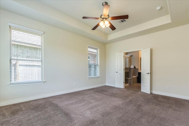 empty room featuring a raised ceiling, visible vents, and plenty of natural light