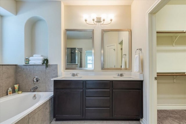 full bath with a garden tub, double vanity, a spacious closet, and a sink