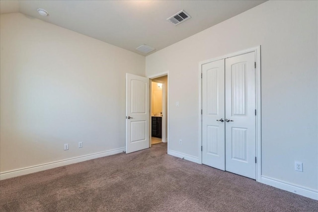 unfurnished bedroom with carpet flooring, visible vents, baseboards, vaulted ceiling, and a closet