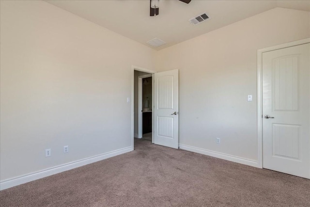 carpeted spare room with vaulted ceiling, visible vents, ceiling fan, and baseboards