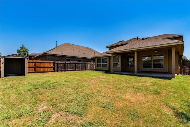 back of house featuring a yard, a storage shed, ceiling fan, a fenced backyard, and an outdoor structure