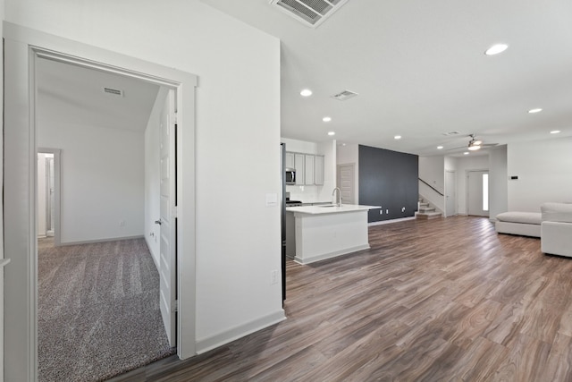 unfurnished living room with carpet, sink, and ceiling fan